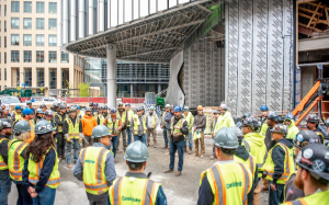 Group of construction workers circled around a worker at an active jobsite