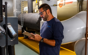 Man looking at clipboard in front of a screen